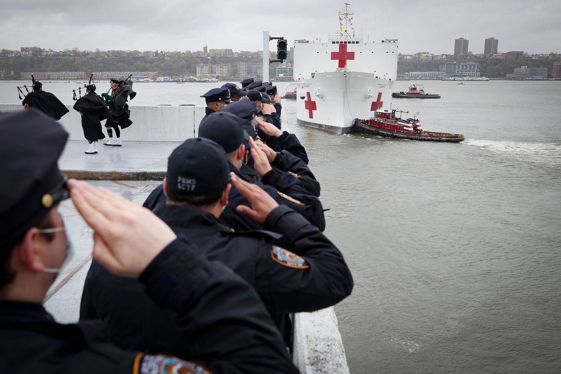 Officers salute the USNS Naval Hospital Ship Comfort as it is pushed out into the Hudson River by tugboats, in  Manhattan